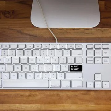 Computer keyboard with black friday key and shopping cart. Copy space and woo Фото