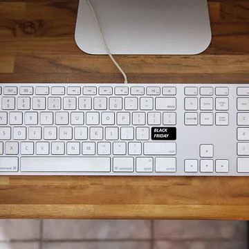 Computer keyboard with black friday key and shopping cart. Copy space and woo 库存照片