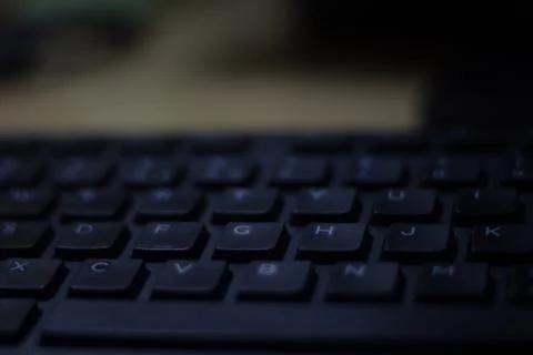 Computer keyboard closeup in black backlight Stock Photos