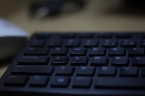 Computer keyboard closeup in black backlight Stock Photos