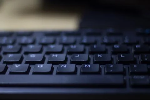 Computer keyboard closeup in black backlight Stock Photos