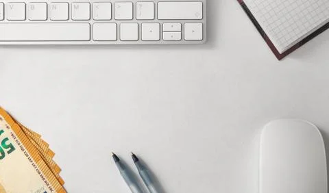 Computer keyboard, computer mouse, ballpoint pens, notebook and money. Stock Photos