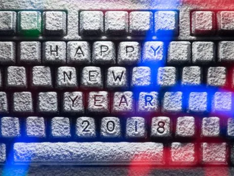 Computer keyboard covered with snow with title happy new year 2018 lit by col Foto stock
