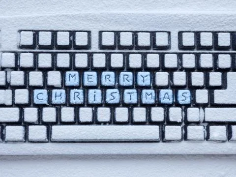 Computer keyboard covered with white snow with inscription merry christmas on Foto stock