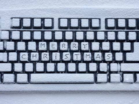 Computer keyboard covered with white snow with inscription merry christmas 스톡 사진