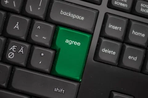 Computer keyboard with a green agree button. Stock Photos