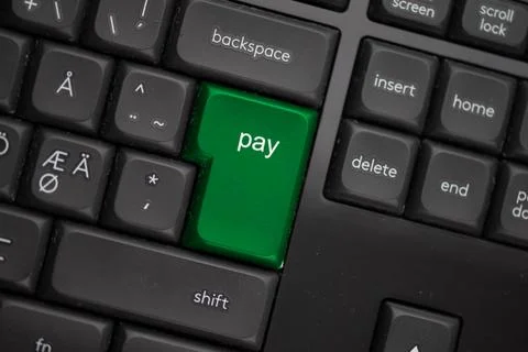 Computer keyboard with a green pay button. Stock Photos
