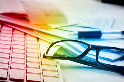 Computer keyboard, pair of glasses, pencil and messy papers lying on a table. Foto stock