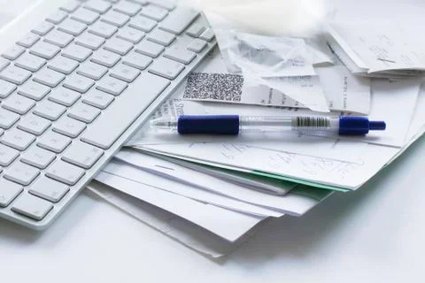 Computer keyboard, pencil and messy papers, lying on a white table Stock Photos