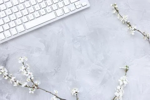 Computer keyboard on spring gray background with white cherry blossom flowers Foto stock