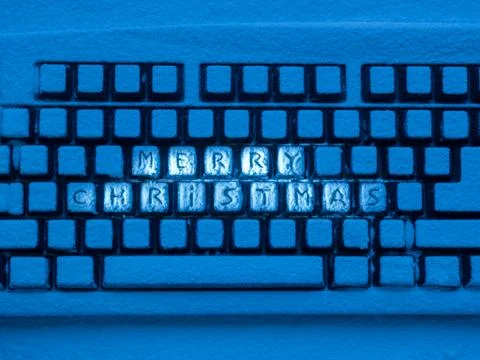 Computer keyboard with text merry christmas on buttons covered with snow Foto stock
