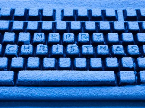 Computer keyboard with text merry christmas on buttons covered with snow 스톡 사진