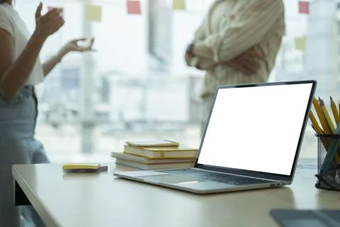 Computer laptop with blank screen and office supplies on wooden table at crea Stock Photos