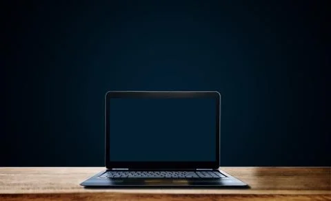 Computer laptop empty blue screen on wooden desk, on dark blue background Foto stock