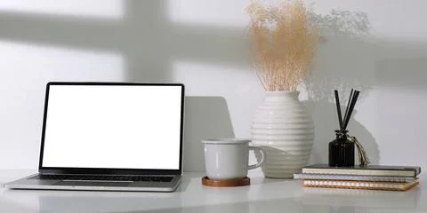 Computer laptop with empty screen, coffee cup, and potted plant on table. Hom Stock Photos