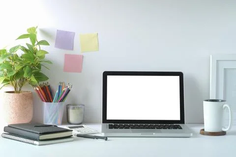 Computer laptop with empty screen, houseplant, picture frame and stationery o Stock Photos
