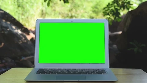 Computer laptop with green screen display near the creek. Stockbeeldmateriaal 97856878