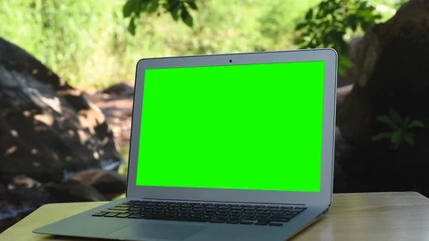Computer laptop with green screen display near the creek. 库存影片 97857460