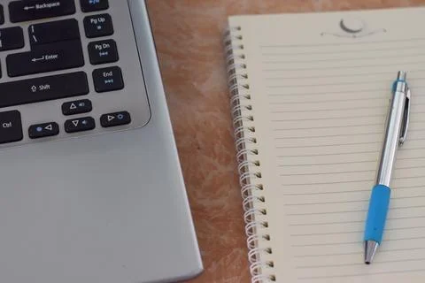 Computer laptop, notebook and pen on work office desk. (selective focus) Stock Photos