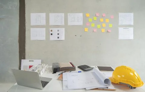 A computer laptop notebook, hardhat, paperwork, equipment and structure drawi Stock Photos