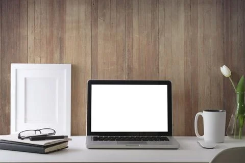 Computer laptop with white empty display, picture frame, books and coffee cup Stock-Fotos