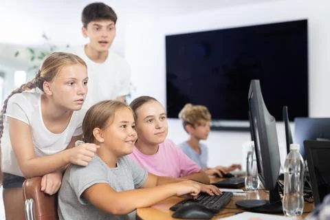 Computer lesson in classroom - classmates solve problems on computer together Stock Photos