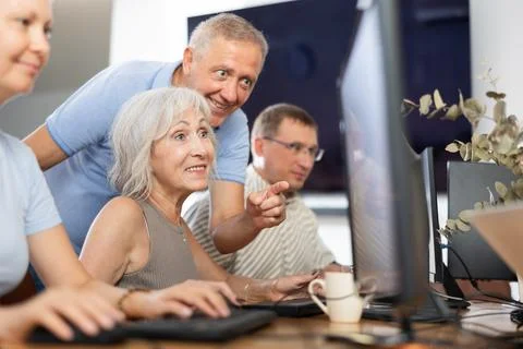 Computer literacy training in nursing home - teacher helps elderly people learn Stock Photos