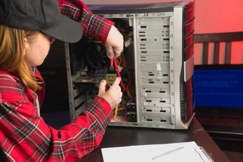 The computer master in the cap inserts special parts to repair the processor. Stock Photos