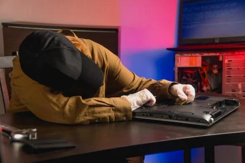The computer master fell asleep while working behind a laptop on the table. T Stock Photos