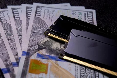 Computer memory module placed on top of hundred dollar bills with dark Stock Photos