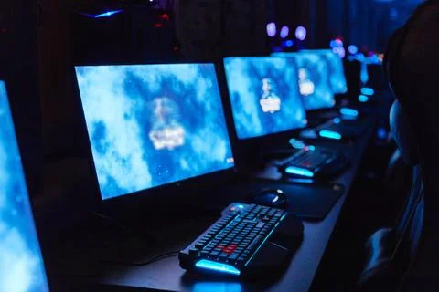 Computer monitors and keyboards standing in a row on tables, running in the dark Stock Photos