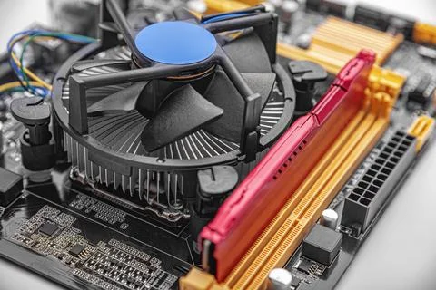A computer motherboard featuring a CPU cooling fan and a RAM module installed in Stock Photos