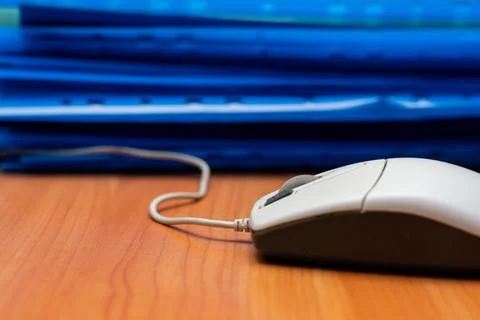 Computer mouse and blue files arranged on desk on a workday 写真素材