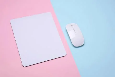 Computer mouse and square mouse pad on pastel pink and blue background Stock Photos