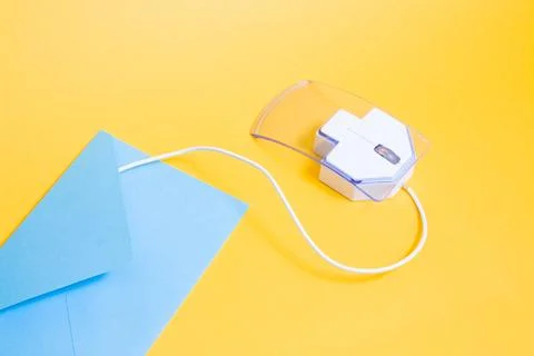 Computer mouse made of transparent plastic and paper blue envelope on a yello Stock Photos
