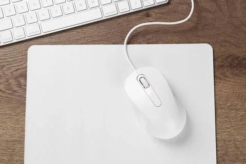 Computer mouse with mousepad and keyboard on wooden table, flat lay Stock Photos