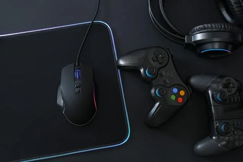 Computer mouse, mousepad, headset and game controllers on black background,.. Stock Photos