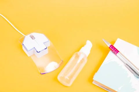 Computer mouse notepad pen and gel alcohol antiseptic on a yellow background  Stock Photos