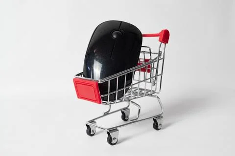 Computer mouse placed inside a miniature shopping cart isolated on white ba.. Stock Photos