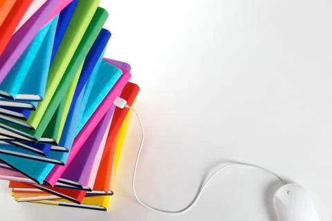 Computer mouse plugged into stack of rainbow-colored books Foto stock
