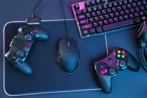 Computer mouse, RGB keyboard and game controllers on black background, top vi Stock Photos