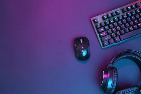Computer mouse, RGB keyboard and headset in neon lights on dark background,.. Foto stock