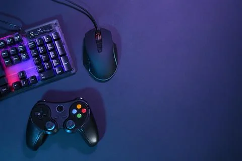 Computer mouse, RGB keyboard and game controller on dark background, flat l.. Stock Photos