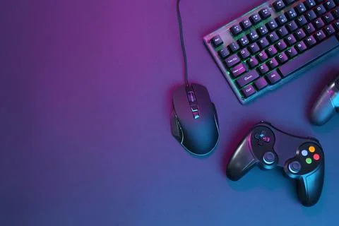 Computer mouse, RGB keyboard and game controllers in neon lights on dark ba.. Foto stock
