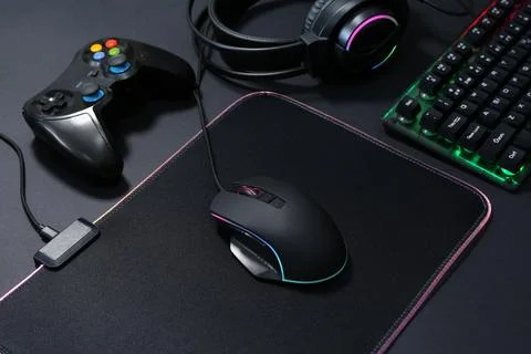 Computer mouse, RGB keyboard, game controller and headset on black background Stock Photos