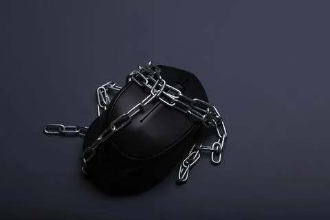 Computer mouse wrapped in chains on dark surface Stock Photos