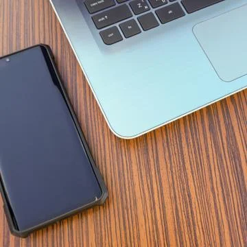 Computer notebook with black smartphone and a blue pencil on a wooden desk. Stock Photos