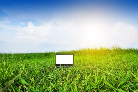 Computer notebook in green field under blue sky.Blogger Sky and Clouds Stock Photos