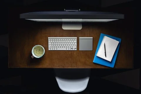 Computer, notepads and a cup of tea on the desktop at night, top view. Stock Photos