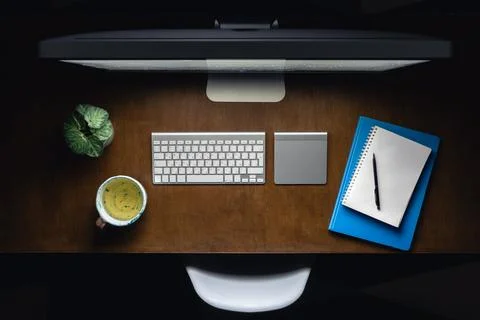 Computer, notepads and a cup of tea on the desktop at night, top view. Stock Photos